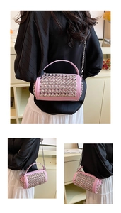 Detail of pink cylindrical PU bag featuring silver rivets and metal chain strap