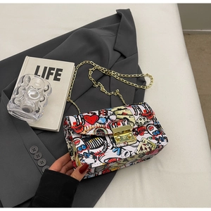 Detailed view of the pop art graffiti print and gold chain strap on the stylish crossbody bag