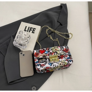 Detail of colorful graffiti print crossbody bag with golden chain on grey blazer