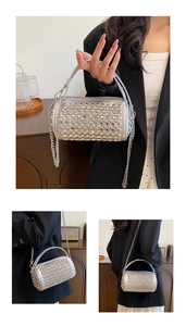 Macro detail of silver rhinestone cylinder clutch bag with metal ring handle and chain
