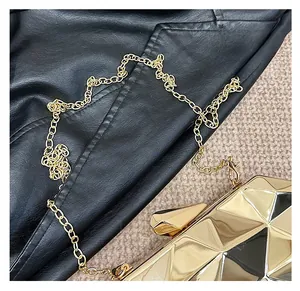 Detail of gold geometric faceted metal clutch bag with slim metallic chain strap
