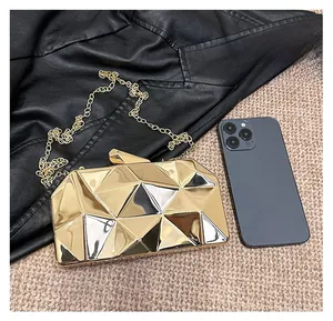 Golden geometric clutch evening bag with metal chain shown next to a smartphone for scale