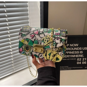Detailed view of colorful graffiti print and gold metal clasp on small crossbody bag