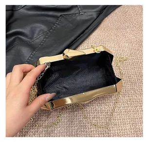 Detail view of the elegant gold clutch bag interior with black lining and golden chain strap