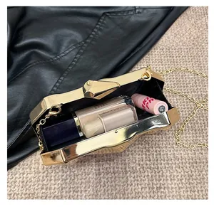 Detail of gold evening clutch box bag showing interior capacity with lipstick and makeup