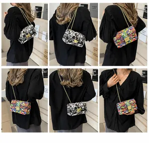Detail of trendy graffiti crossbody bag with gold chain strap and metallic press lock