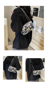 Detail showing graffiti print pattern and gold chain strap on the white crossbody bag