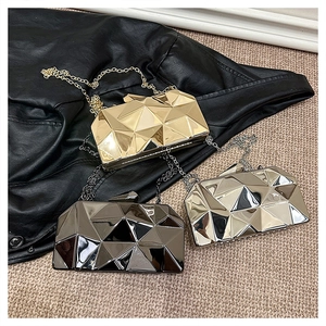 Close-up of three geometric metal clutch bags in gold, silver and black with chain straps