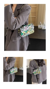 Close-up of artistic graffiti print crossbody bag with golden chain and metal lock