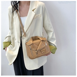 Street style shot of a caramel biker jacket shoulder bag with studs and metal zippers