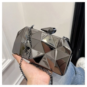 Macro detail of gunmetal geometric box bag featuring polished 3D faceted finish and chain