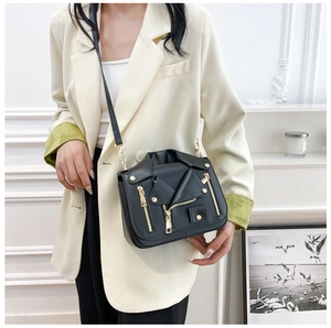 Detailed view of black motorcycle jacket style crossbody bag with gold stud accents