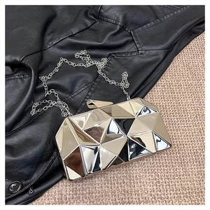 Macro view of geometric silver clutch bag with faceted diamond texture and silver chain strap