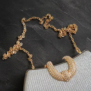 Detail of silver glitter evening clutch featuring rhinestone hardware and gold chain strap