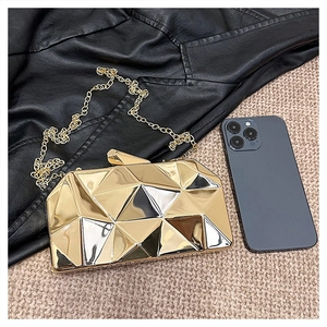 Macro shot of gold geometric evening clutch bag with metallic mirror finish and chain