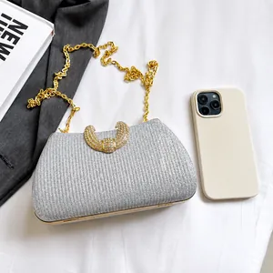 Silver glitter evening clutch with rhinestone clasp and gold chain beside a smartphone