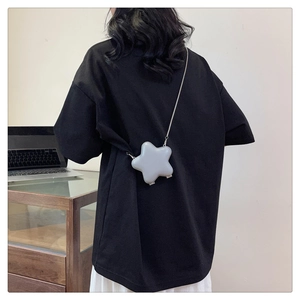 Mini sac bandoulière argenté en forme d'étoile avec chaîne en métal sur tenue noire