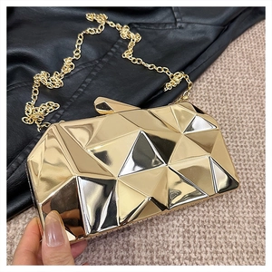 Detail of golden geometric mirror clutch bag with metallic chain on textured background