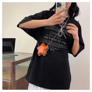 Détail d'un mini sac orange en forme d'étoile avec finition brillante et chaîne argent