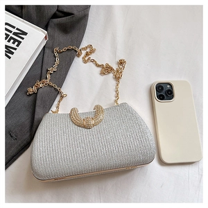 Macro shot of silver glitter evening bag with U-shaped rhinestone buckle and gold chain