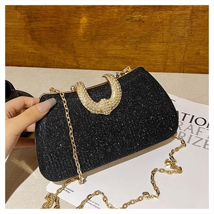 Detail of black glitter evening clutch with gold chain strap and crystal-studded clasp