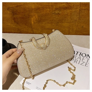 Close-up of champagne gold evening bag with glitter finish and sparkling diamond U-clasp
