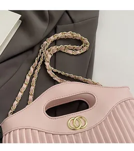 Macro detail of pink pleated handbag showing golden double ring buckle and chain strap
