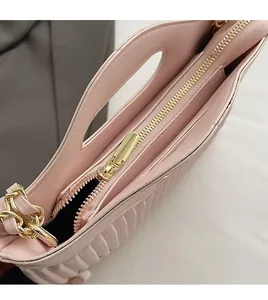 Detail of pink pleated leather tote bag with smooth golden zipper and braided chain strap