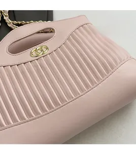 Detail of light pink tote bag featuring vertical matelassé stitching and gold hardware