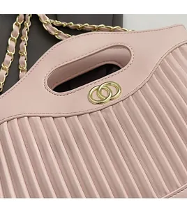 Detail of pink pleated leather bag featuring golden double-ring buckle and chain strap