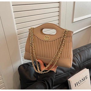 Close-up of beige pleated handbag featuring a gold double ring clasp and metal chain