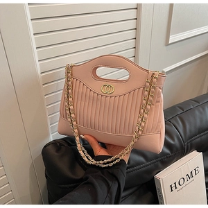 Pink quilted faux leather handbag detail with golden chain and ring hardware on black sofa