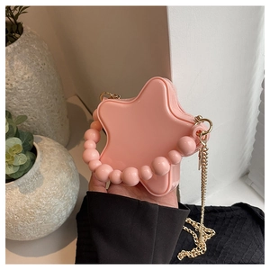 Detail of pink star-shaped mini bag with bead handle and gold chain strap in hand