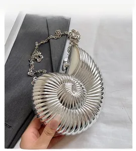 Detailed view of silver nautilus shell evening bag with metallic chain and spherical lock