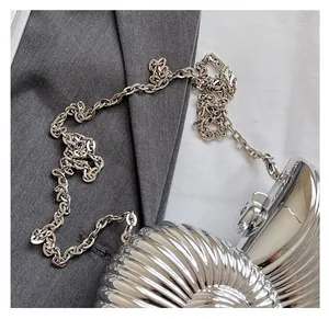 Detail of silver shell-shaped evening bag with glossy metallic texture and chain strap