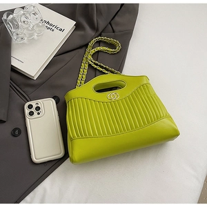 Detail of lime green pleated tote bag with golden chain strap and buckle on grey suit