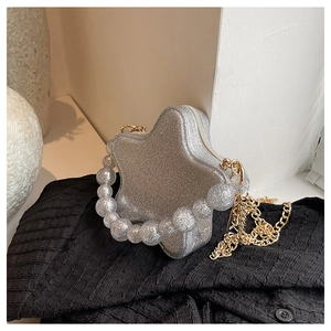 Macro detail of a silver glitter star bag with large pearl handle and gold metal chain