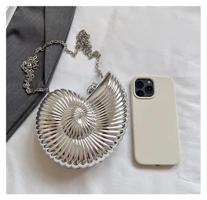 Detailed size comparison of the shell-shaped evening bag with chain strap next to a phone