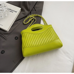 Detail of lime green pleated tote bag with chain strap on a stylish gray blazer
