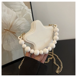 Detail of white star-shaped bag with pearl handle and golden chain on artistic background