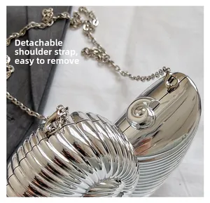 Detail of silver shell-shaped metallic clutch with detachable chain strap and spiral texture