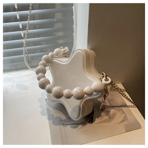 Close-up of a star-shaped white purse with pearl handle and golden chain detail