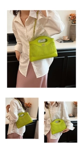 Detail view of grass green pleated tote bag with golden metal hardware and chain strap