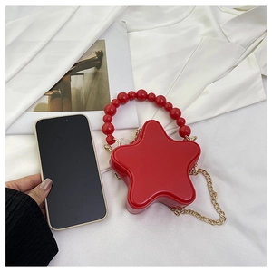 Macro shot of red star-shaped mini bag with pearl handle and golden chain detail