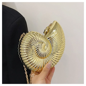 Detailed view of a metallic gold seashell clutch bag worn over a black blazer with chain
