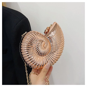 Macro detail of rose gold nautilus clutch bag with spiral metal texture and chain strap