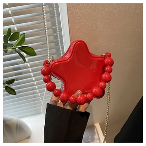 Macro detail of red star-shaped mini bag with glossy finish and red beaded handle