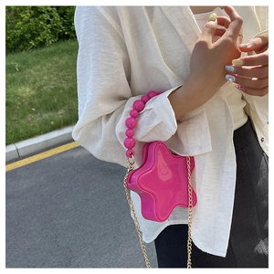 Detail of star-shaped bright pink bag with matching chunky pearl handle and gold chain strap