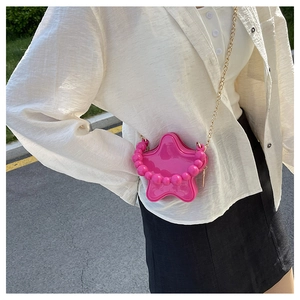 Detail of pink star-shaped crossbody bag with gold chain and large pearl handle