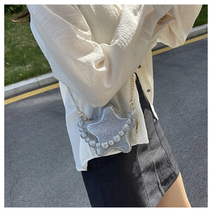 Detail of silver glitter star-shaped purse with pearl handle and gold chain strap